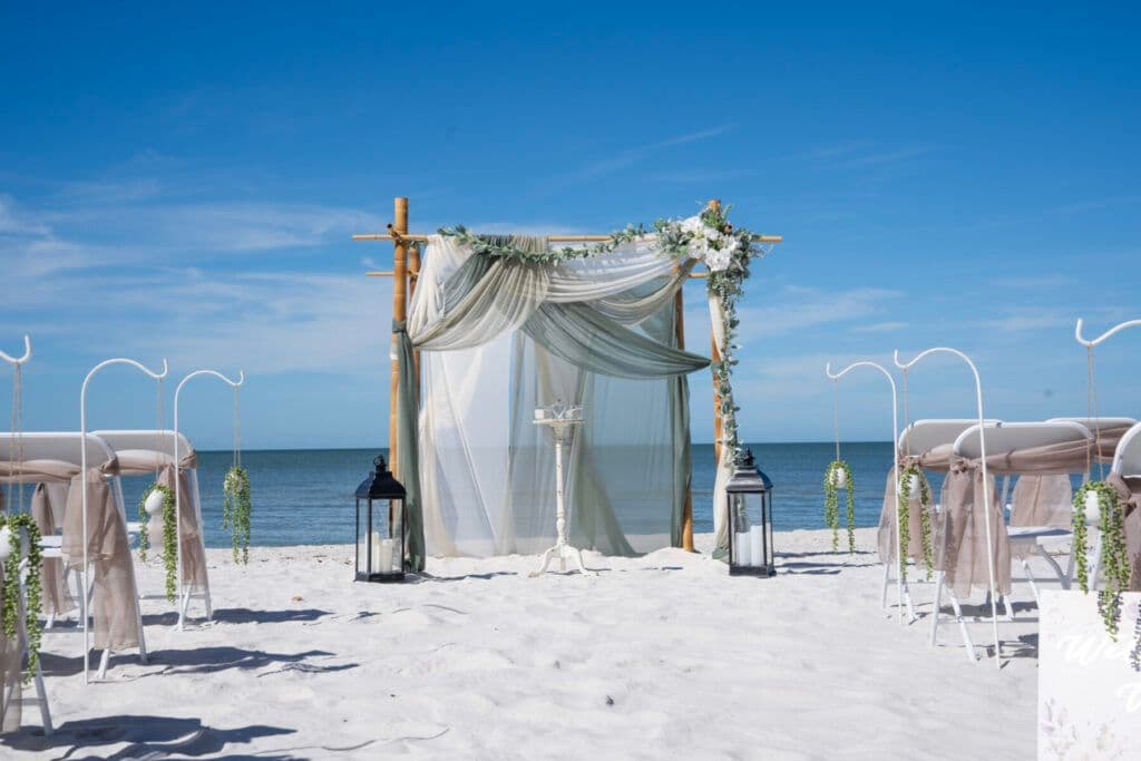 Four-post bamboo canopy with sage draping and florals on a Florida beach