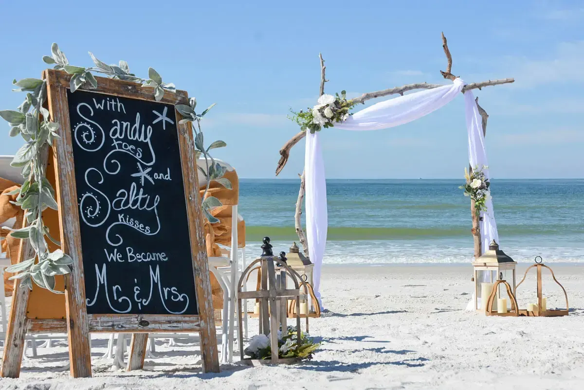 Beach wedding setup with a chalkboard sign that reads