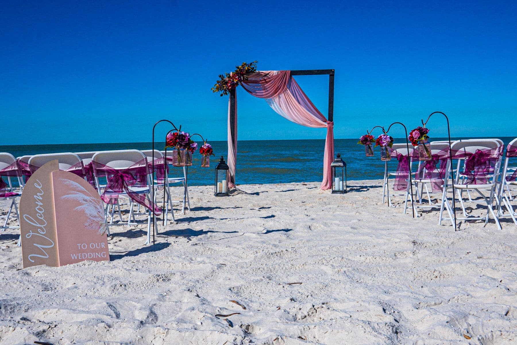 Beach wedding setup with arch, chairs, and