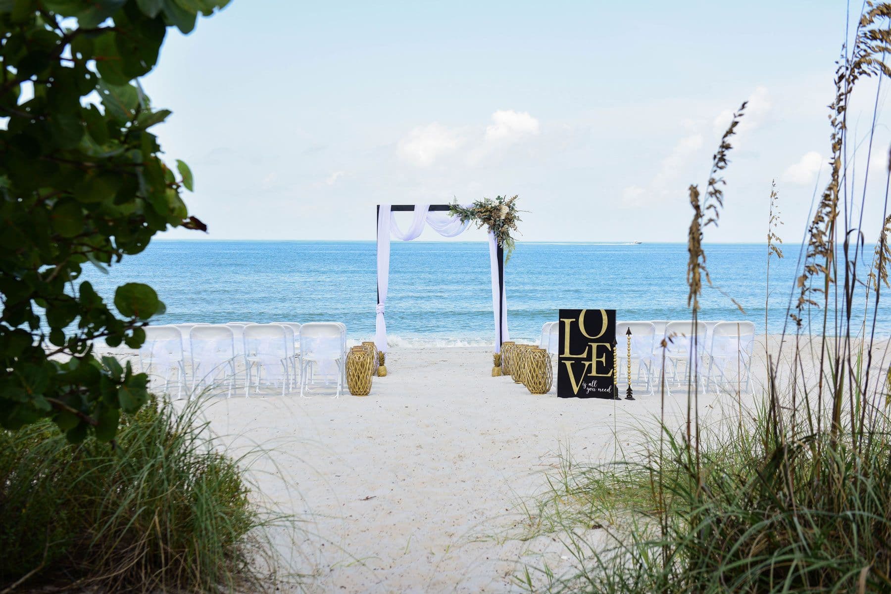 Beach wedding setup with ocean view: arch, chairs,